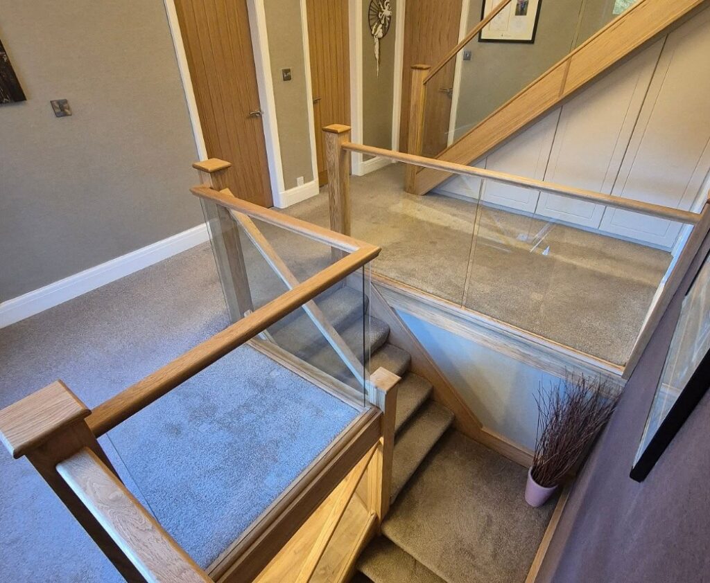 Glass staircase renovation with oak handrails and clear glass panels in Cheshire